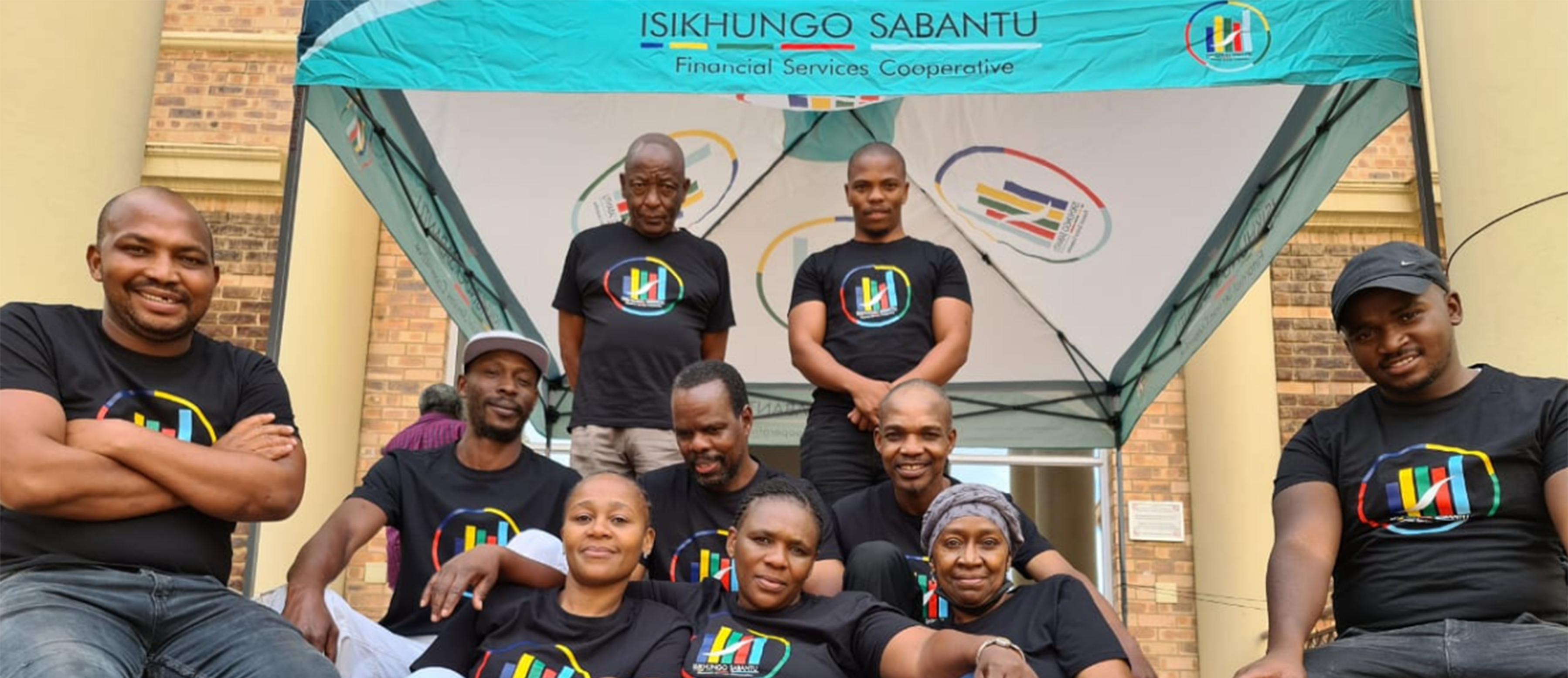 A group of shareholders from Isikhungo Sabantu Financial Services Cooperative (IS FSC) CFI under the IS FSC branded gazebo